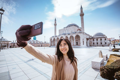 Portrait of young woman standing against sky