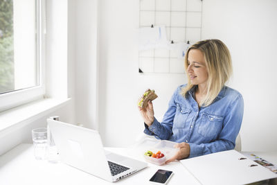 Businesswoman eating food while sitting at home office