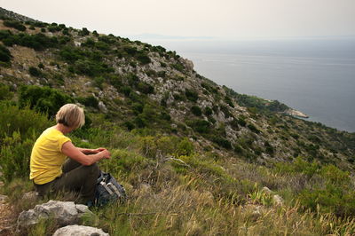 Senior woman sitting on mountain peak with beautiful view on adriatic sea