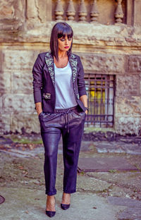 Portrait of young woman standing against wall