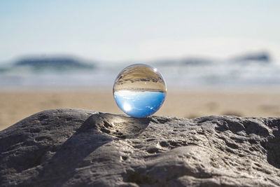 Photography crystal photo ball showing upside down reflection of sky beach and waves on rocks 