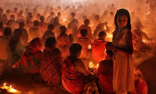 A girl is looking at camera while people are praying at rakher upobash