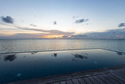 View of a infinity pool near the ocean at sunrise