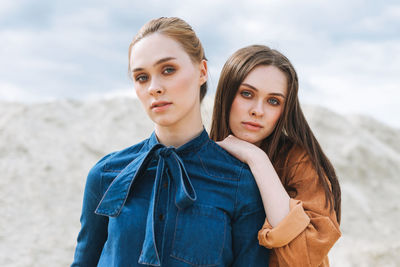 Fashion beauty portrait of young women sisters in brown velvet jeans shirts on the desert background