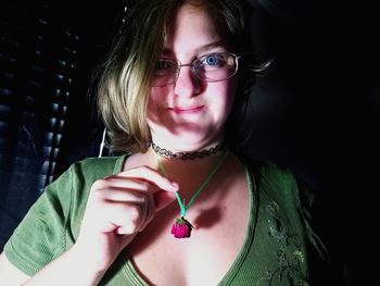 Close-up portrait of young woman wearing rose in neck