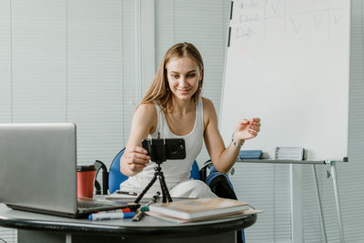 Young woman using phone while sitting on table