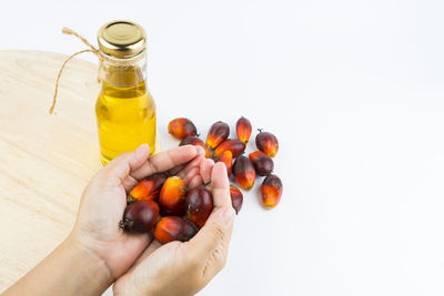 Cropped image of person holding fruit against white background