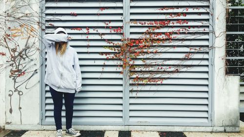 Full length of girl covering face with hand by door