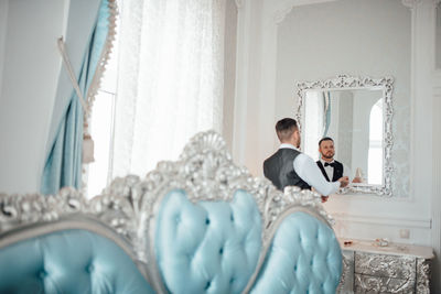 Man and woman standing against white window