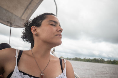 Portrait of young woman looking away against sky