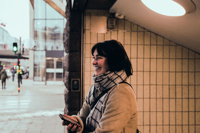 Young woman looking through mobile phone while standing on mirror