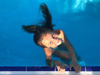 High angle portrait of smiling girl swimming in pool
