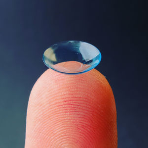 Close-up of hand holding glass against blue background