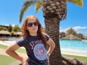 Portrait of young woman wearing sunglasses while standing at beach