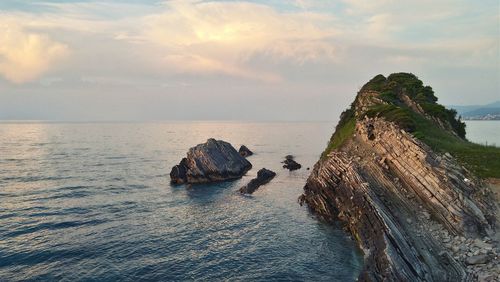 Rocks on sea against sky during sunset