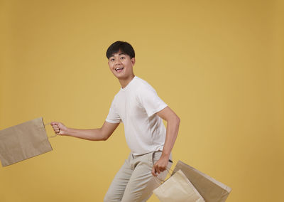 Portrait of smiling young woman standing against yellow wall