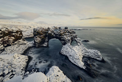 Rocks in sea during sunset in winter