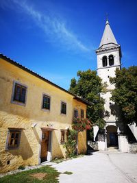 Picturesque scene from mediterranean village with yellow-walled house and church tower