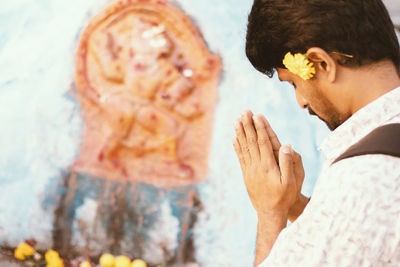 Man praying against statue