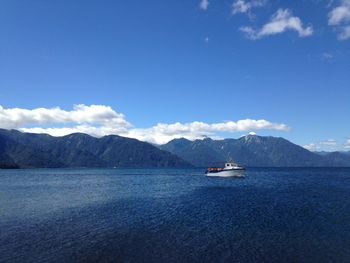 Boats in sea against cloudy sky