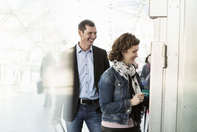 Happy business colleagues buying tickets at railroad station