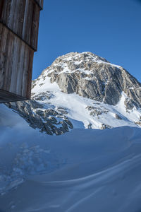 Low angle view of snowcapped mountains against clear blue sky