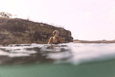 Happy woman sitting on surfboard in sea