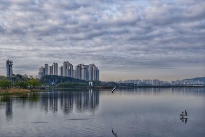 Scenic view of lake by buildings against sky in city