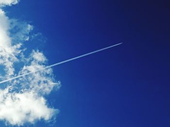 Low angle view of vapor trail in blue sky