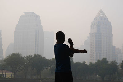 Rear view of man standing by buildings against sky