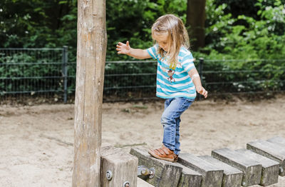 Full length of girl walking on wood in park