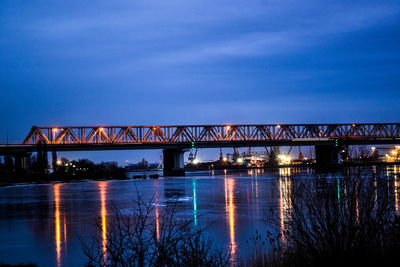 Illuminated bridge over river against sky at night