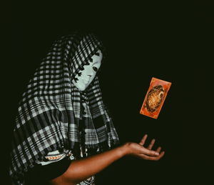 Midsection of person holding umbrella against black background