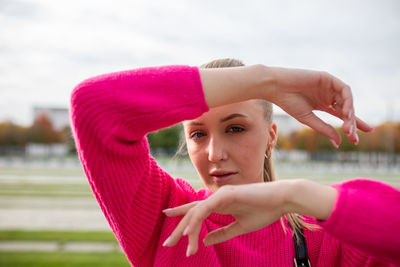 Portrait of young woman gesturing while standing outdoors