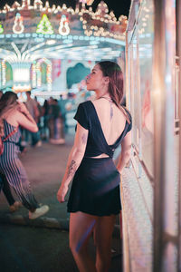 Woman standing in amusement park at night