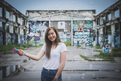 Portrait of smiling young woman standing in city