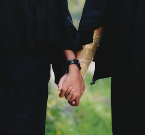 Midsection of couple holding hands