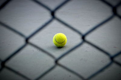 Close-up of yellow ball on metal fence