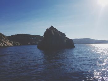 Rock formation in sea against blue sky