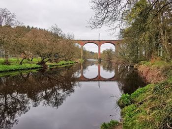 Arch bridge over river against sky