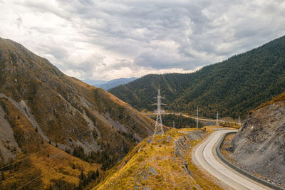 Highway through the mountains, high mountains on each side, power lines and green forest