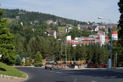 Road by trees against sky in city