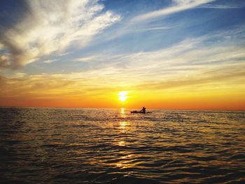 Silhouette person in sea against sky during sunset