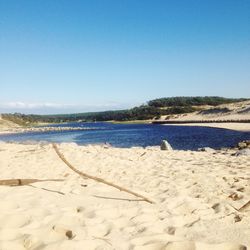 Scenic view of beach against clear blue sky