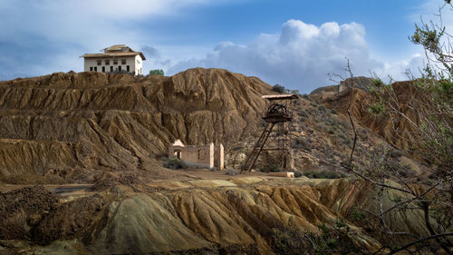 Built structure on rock by buildings against sky