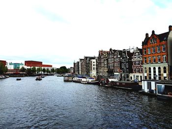 Canal amidst buildings in city against sky