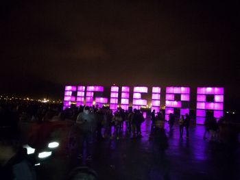 Crowd at music concert against sky at night