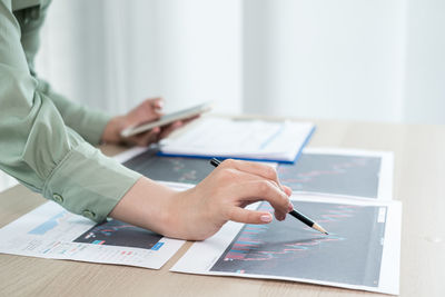 Midsection of businesswoman analyzing data on desk in office