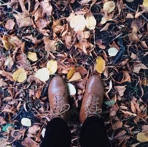 Low section of woman standing on autumn leaves