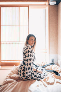 Portrait of young woman sitting on bed at home in japan